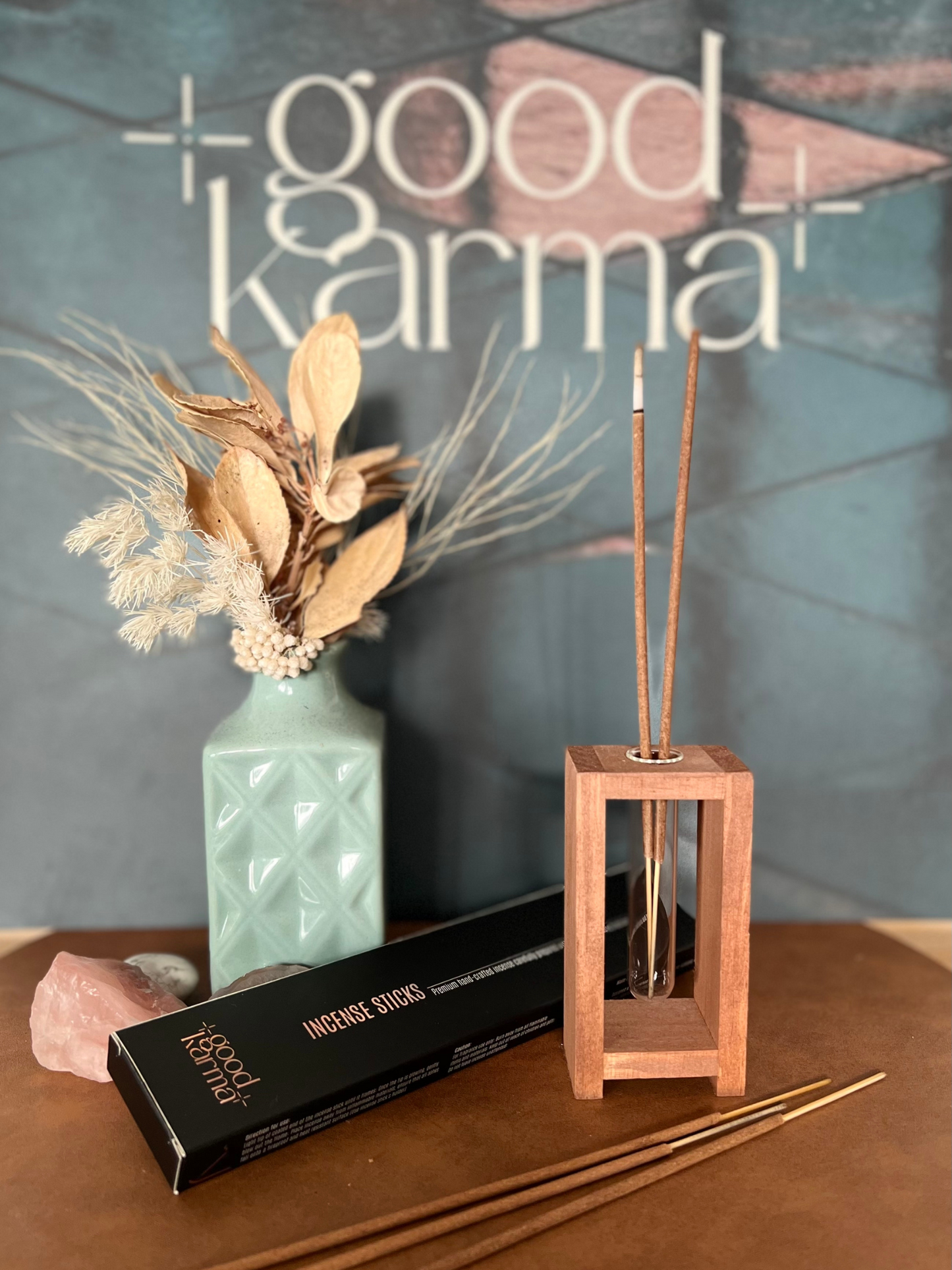 Good Karma Handcrafted incense sticks packs with Incense burning on Incense sticks holder and vase and logo board on the background