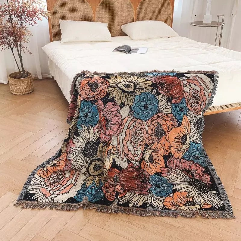 Flowers pattern on black background fabric Woven Boho Quilt Colorful Bohemian Tapestries with tassels thrown on the corner of the bed with white bedsheets