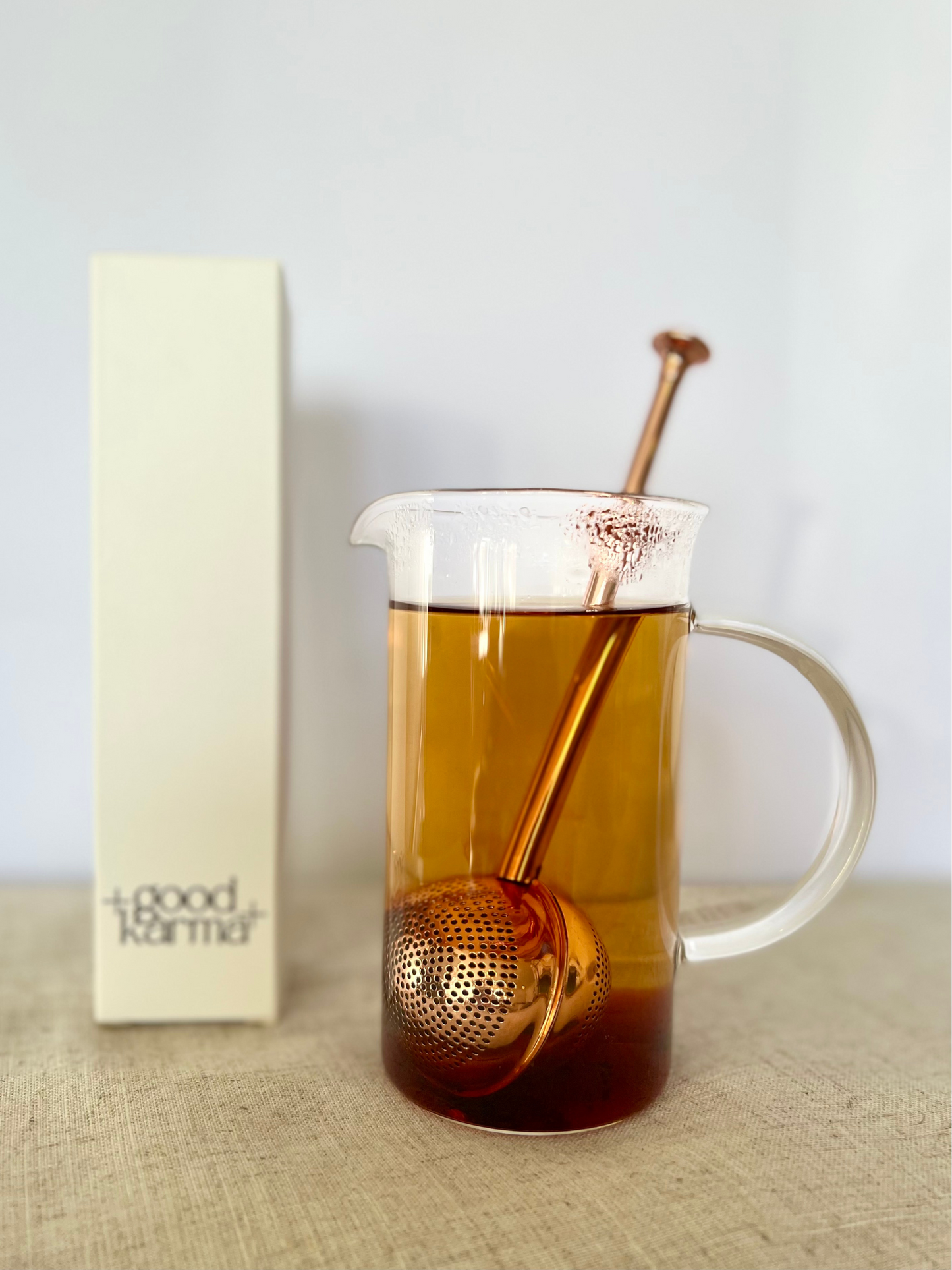 Good Karma tea infuser ball is 2-in-1 scoop and a strainer rose gold color inside transparent cup of tea with white box