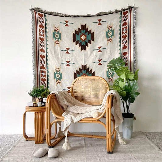 Aztec pattern Woven Boho Quilt Colorful Bohemian Tapestries with tassels hanging on white background wall behind the rattan chair