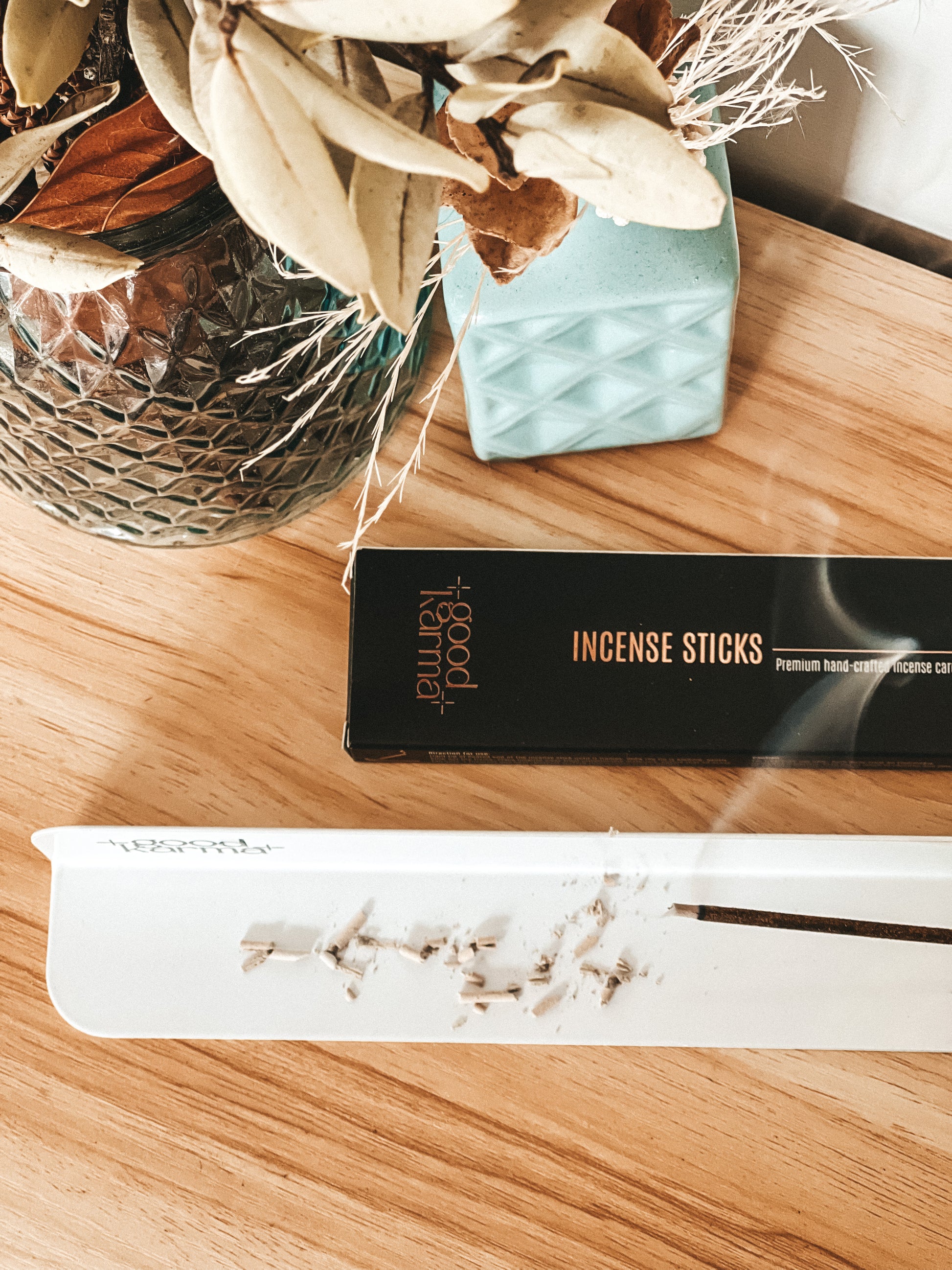 white metal incense sticks holder incense burner with one incense stick with pack of Good Karma incense on the table
